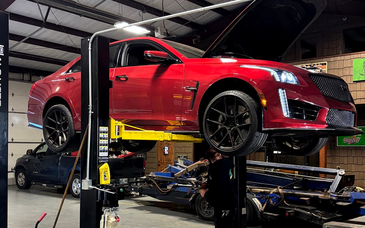 Red performance sedan raised on a lift for suspension work