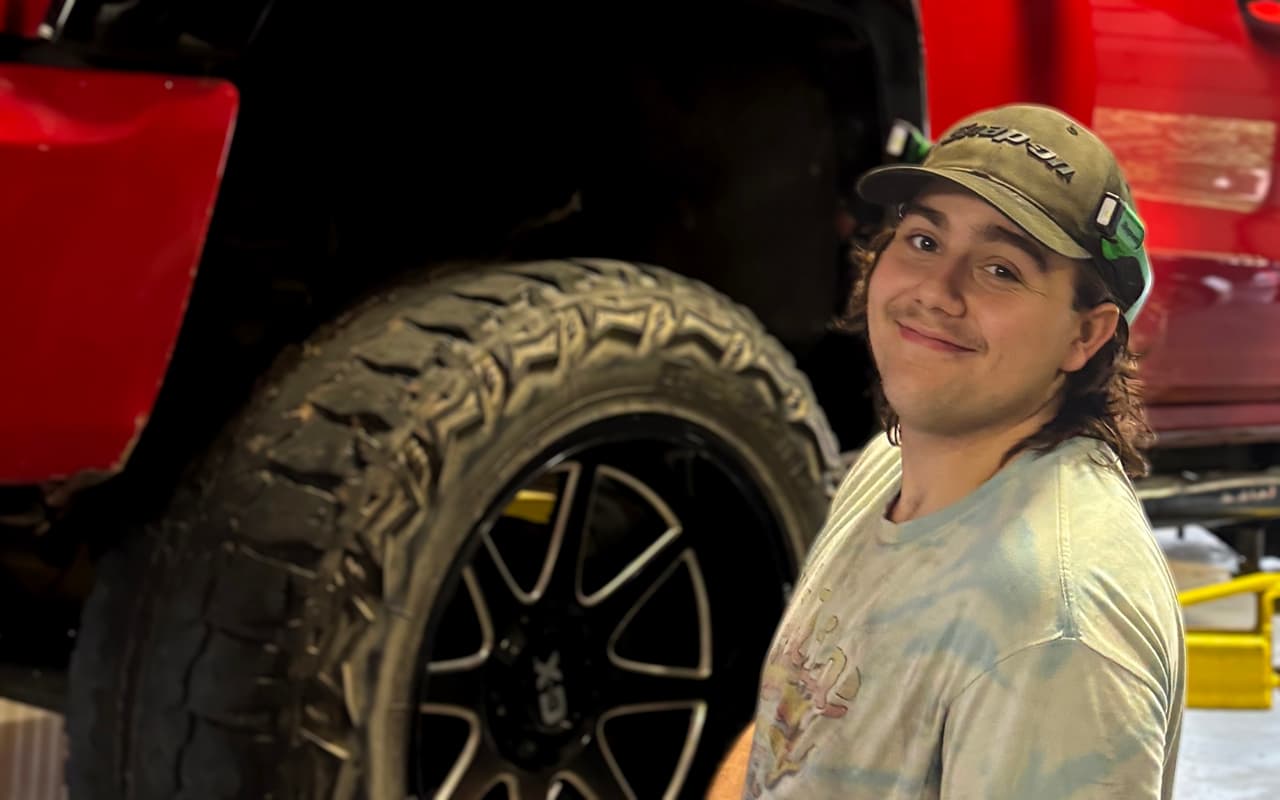 Noah servicing a lifted red truck at Impact Auto Repair