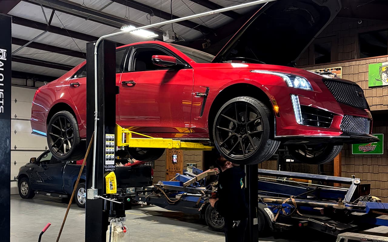 Red performance sedan raised for drivetrain service