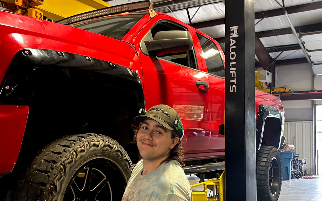 Technician working near a lifted truck wheel