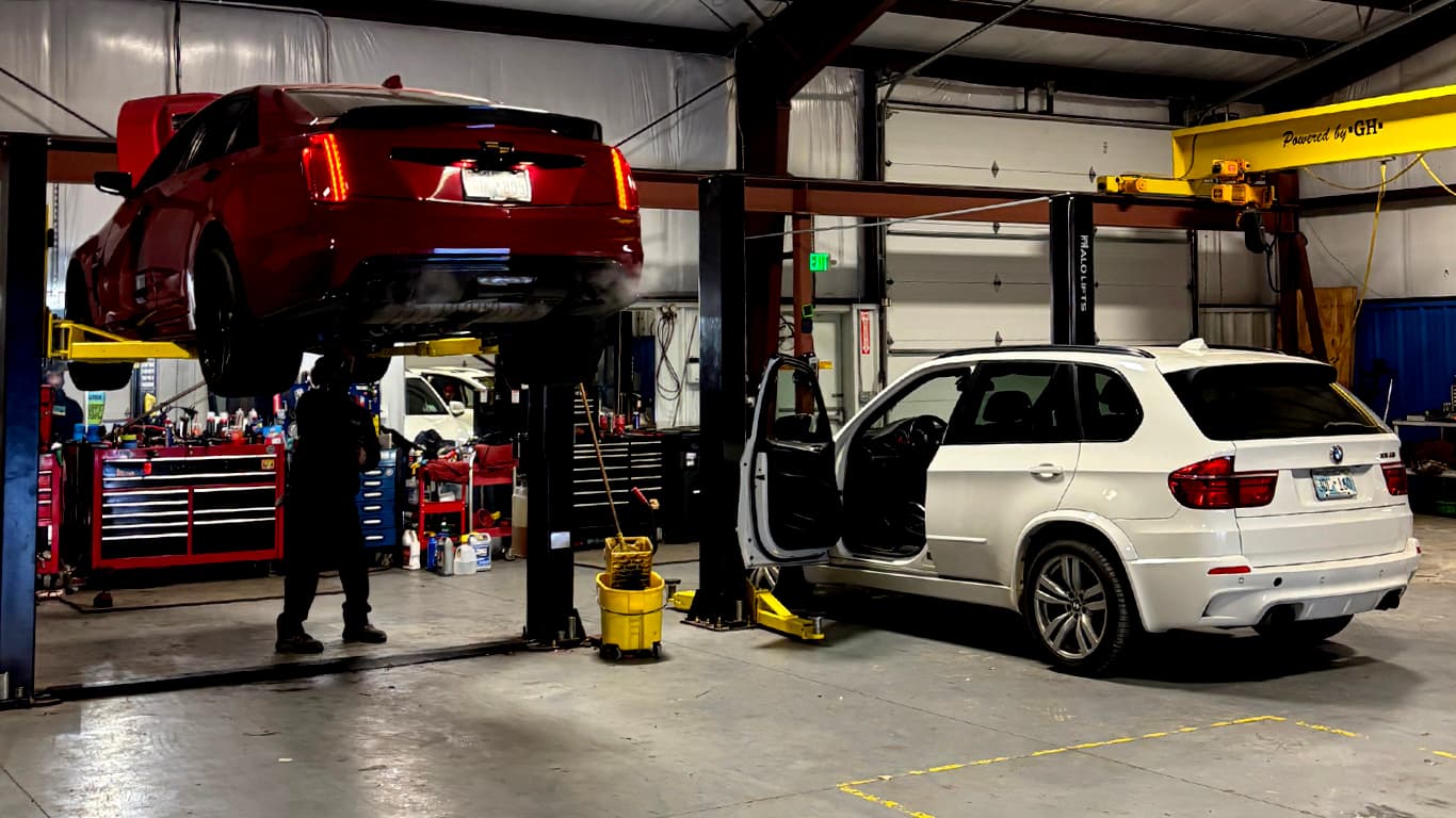 Vehicle raised on a lift inside Impact Auto Repair